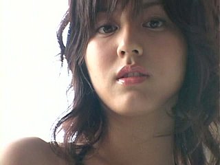 Verleidelijke Japanse babe yumi sugimoto poseert op een strand met haar magere lichaam